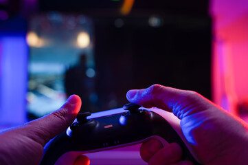 Joystick in the hands of a gamer. Technological background. Close-up. Video games, entertainment, online competition with friends, recreation, game strategy, new emotions.