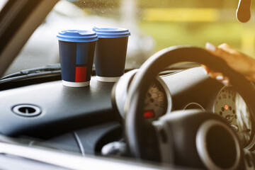 two blue paper coffee cups on car dashboard. Paper Cup with hot tea. young Woman driving. cropped photo. High quality photo