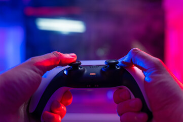 A gamer with a joystick in his hands sits in front of a large TV screen and plays video games with...