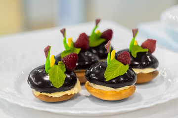 Assortment of delicious fresh shortcrust tart cakes with cream, chocolate and fruits on white plate for sale at restaurant, cafe, bakery: close up. Dessert, sweet food and confectionery concept