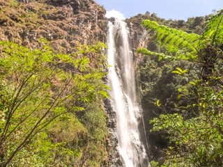 extensive large waterfall surrounded by stones and very green in Ipoema district of Itabira in...