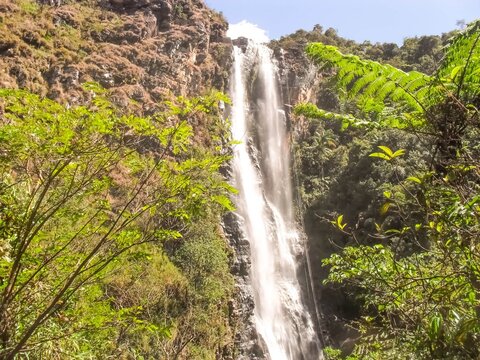 extensive large waterfall surrounded by stones and very green in Ipoema district of Itabira in Minas Gerais in Brazil
