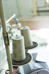 Close-up of a two spools of thread on the industrial sewing machine. A seamstress workplace with a ruller and spool of threads.