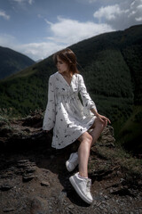 Naklejka premium Elegant young woman in a white dress is posing and looking away.