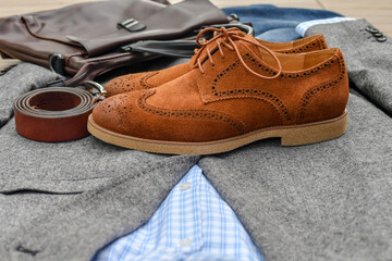 Fototapeta na wymiar A pair of brown suede derby shoes, blue jeans, leather bag and belt with grey tweed blazer. Casual business outlook. Selective focus.