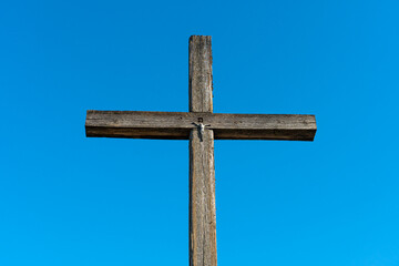 An old wooden cross against a clear blue sky. The crucified Jesus on the cross. The concept of the pure and unrequited love of God Jesus Christ for man.