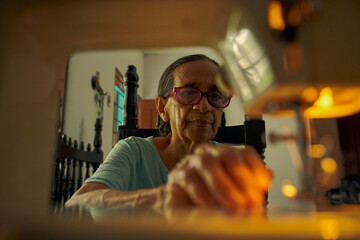 primer plano de mujer anciana colombiana  cosiendo prenda de vestir en una maquina  - obrazy, fototapety, plakaty