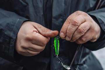 Fisherman changing spinner tail lure on spinning. Fishing on an overcast spring day.