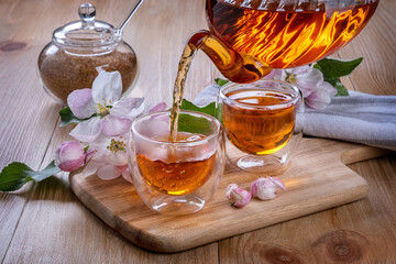 tea is poured into glass cups. apple flowers on the table