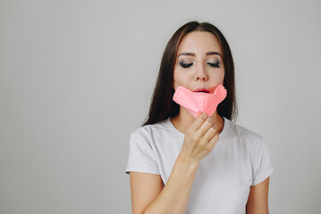 Caucasian girl amid white wall in background wearing pink protective mask, hand made