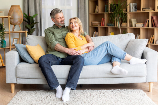 Romantic happy middle aged couple relaxing on couch at home
