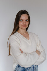 Obraz premium Happy young brunette woman in her 20s over white wall. Employee in casual outfit looking at the camera. Female with long hair, cheerful freelancer business portrait. Copy space