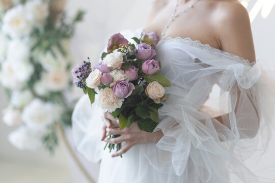 Beautiful attractive caucasian young woman in a white wedding dress with a bridal flower bouquet. Smiling