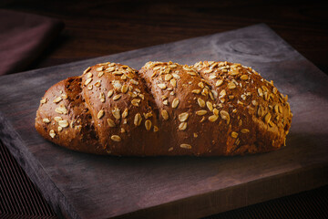 A rustic oat bread, on a wooden board on a fine table