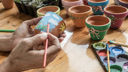 Fototapeta na wymiar Hands of a Latin woman, painting clay pots to plant succulent plants