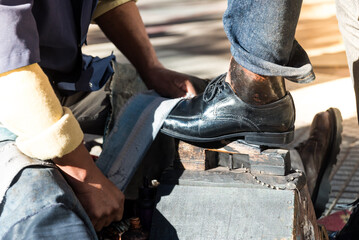 Man polishing leather shoes with a brush. street work concept.