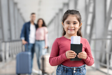 Smiling Little Girl Standing With Passport And Tickets In Hands At Airport