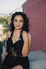 Young woman posing in sexy black dress on the street with high heels