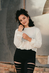 Fototapeta premium Dark haired woman poses in white knit top in front of broken mirror