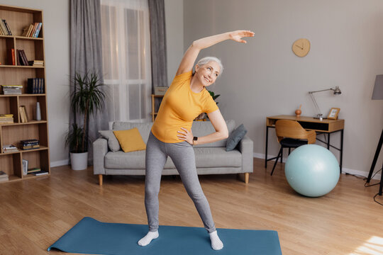 Sport on retirement. Happy senior woman doing flexibility exercises for healthier living during home workout