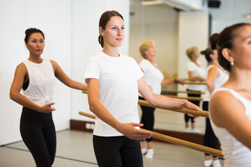 Fototapeta na wymiar Women of different ages exercising ballet moves in training room.