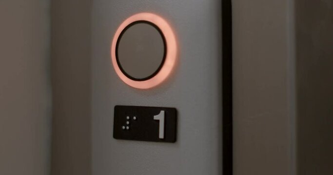 A round button and the number one displayed in Braille. Pressing a finger activates the button and it reacts by changing the backlight along the contour.