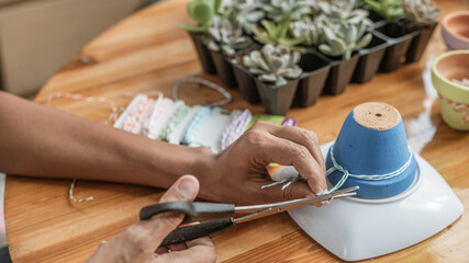 Hands of a Latin woman, painting clay pots to plant succulent plants
