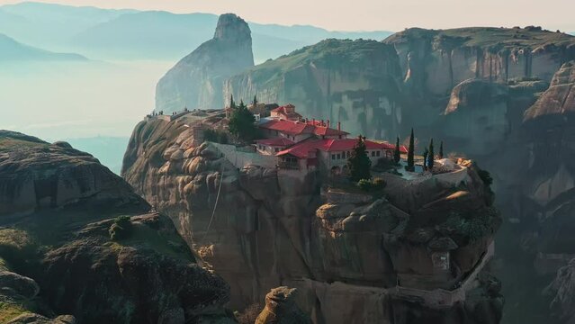 Aerial view of monastery Trinity and breathtaking pictures of valley and landmark canyon of Meteora at sunny day, Kalambaka, Greece, twisted road, Mountains as columns