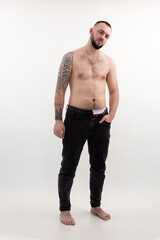 Confident tattooed brutal man with beard and tattoo, shirtless and topless, on whit background....