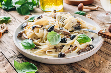 Homemade creamy Italian fettuccine pasta with honey mushrooms. Served on a rustic wooden background.