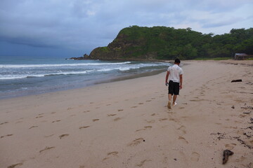 Young boy walking on the sea shore.