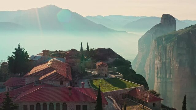Aerial view of monastery Trinity and breathtaking pictures of valley and landmark canyon of Meteora at sunny day, Kalambaka, Greece, twisted road, Mountains as columns