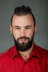 funny guy with a beard in a red shirt close-up shows different emotions. cheerful kind sad surprised satisfied range of emotions