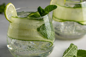 Infused water with cucumber, lime and mint on grey background. Detox beverage.