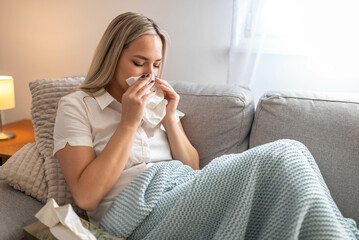 Sick woman sitting under the blanket. Sick woman with seasonal infections, flu, allergy lying in...