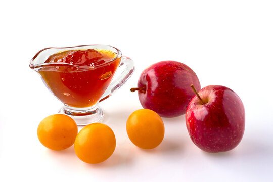 Red cherry plum apples and fruit jam in a glass gravy boat isolated on a white background
