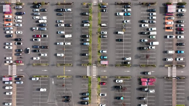 Aerial view of many colorful cars parked on parking lot with lines and markings for parking places and directions