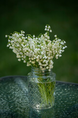 Bouquet of spring flower lilies of the valley on a natural green background of the garden.
