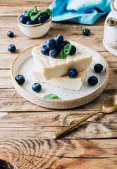 Fresh cottage cheese casserole on white plate on white tile background.