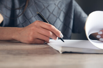 Woman signing document and hand holding pen