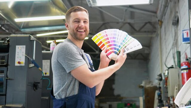 Portrait of an engineer on a printing factory with color palette. Concept of color management in the print production process. Catalog samples for printing proofing