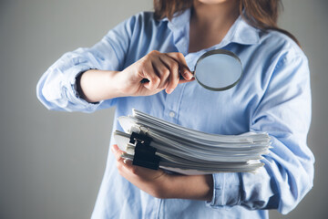 woman with magnifying glass looking at papers