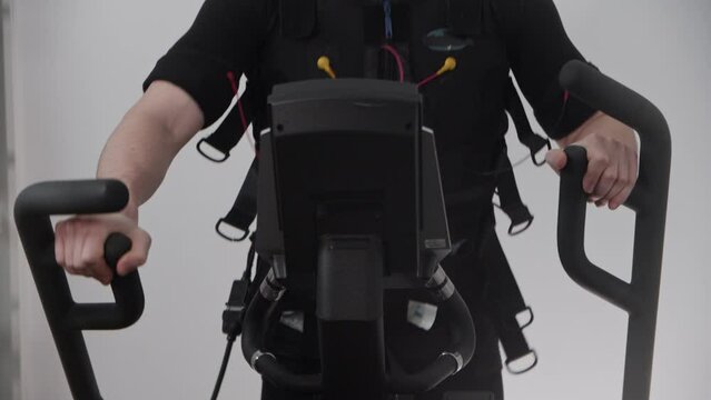 A man wearing electro-stimulation suit and equipment and training on exercise bike