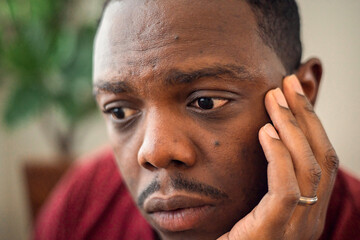 Depressed and anxious African American or black man sitting at home