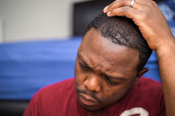 Fototapeta premium Depressed and anxious African American or black man sitting at home