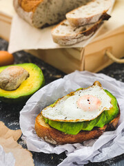 Brunch. Pão rústico em torrada francesa, abacate e ovos fritos. Dark Photography.