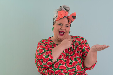 Fototapeta premium Plus size sexy model woman with trendy makeup, fashionable blonde in colorful dress posing at the cyan or light blue background in studio.