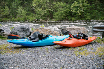 Two single person recreational kayaks and gear along a rapid river for whitewater kayaking sport.