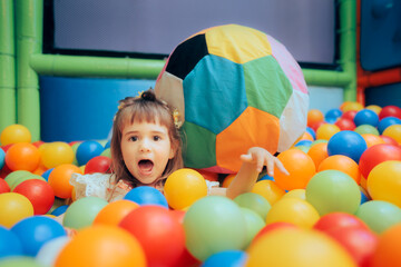 Happy Little Girl Playing in a Ball Pool at a Party