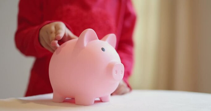 4K Video slow motion asian kid put coin into piggy bank. Concept for financial and saving bank for child.
